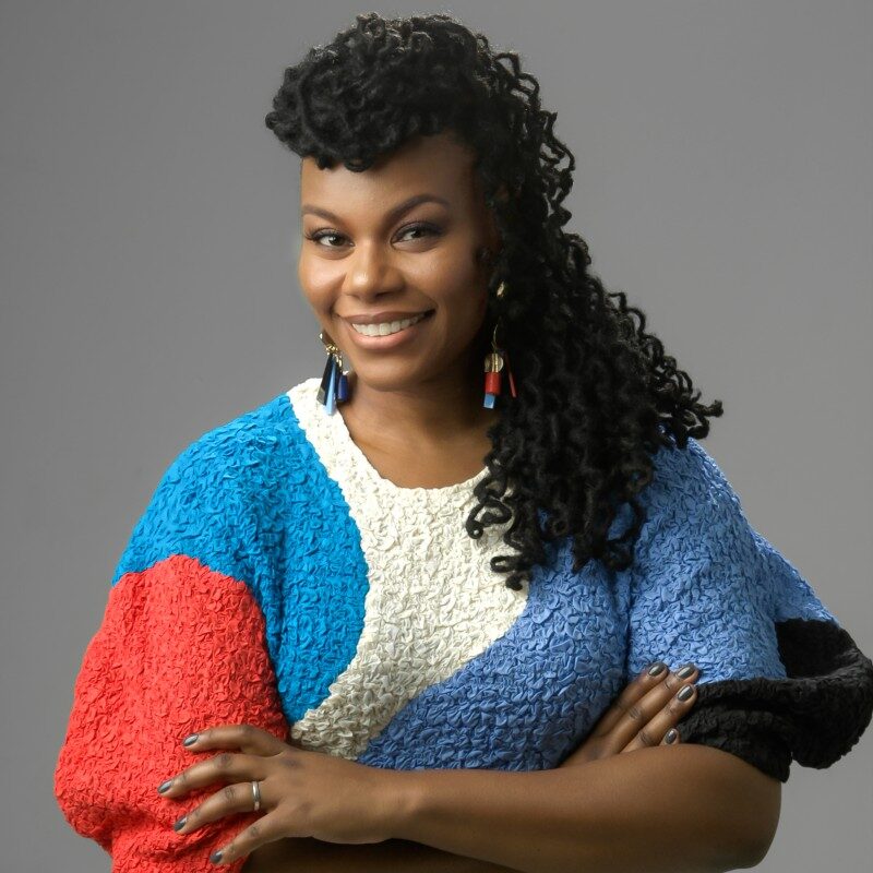 a woman with her arms crossed and smiling at the camera