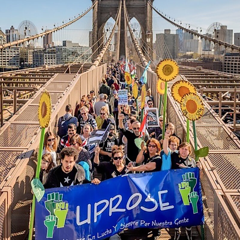 Group of people with an UPROSE banner standing on a bridge in New York City